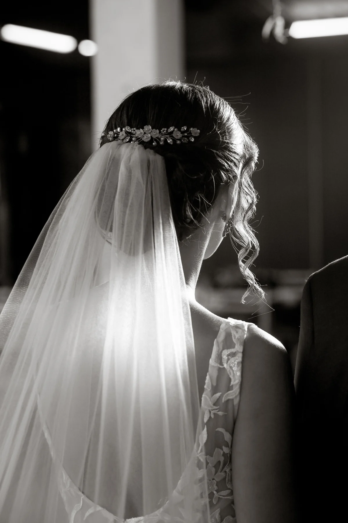 An intimate black-and-white view of a bride’s veil and hair in soft light